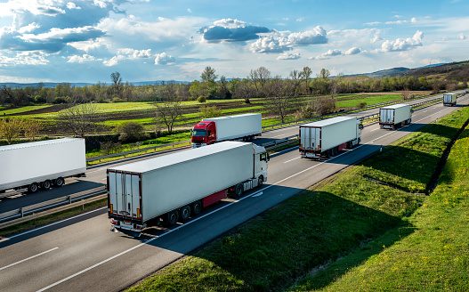 Convoys of transportation Trucks in lines passing each other on a rural countryside highway under a beautiful blue sky