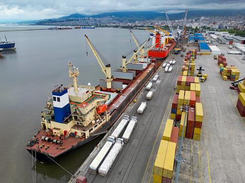 Vancouver, British Columbia, Canada-August 17, 2007- A fleet of orange trucks are busy delivering freight containers to  the massive crane that is loading them onto a waiting ship