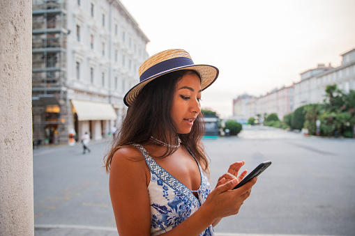 A girl uses her smartphone while staying in the city center in the summer