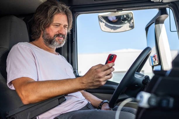 istock Smiling truck driver looking at phone 1549127763