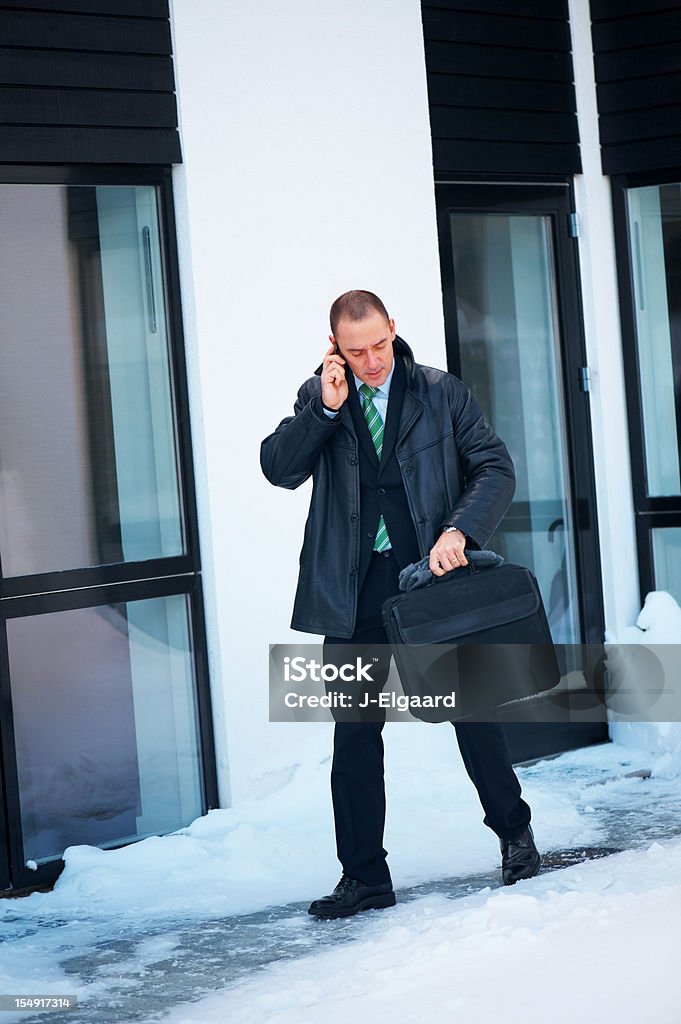 Homme d'affaires élégant à l'extérieur de la maison dans la neige sur le téléphone - Photo de Affaires libre de droits