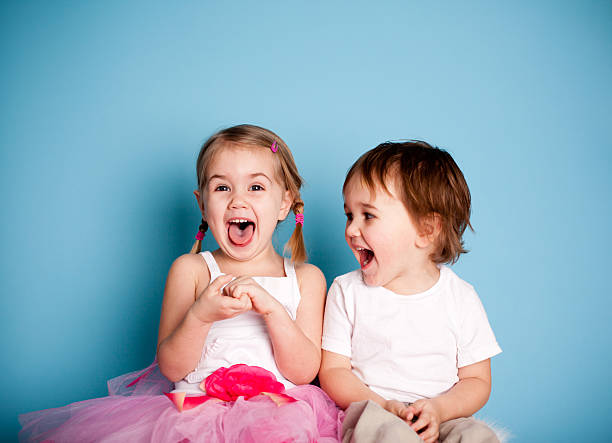 tan divertido. niña y niño sonriente hysterically - little girls small blond hair child fotografías e imágenes de stock