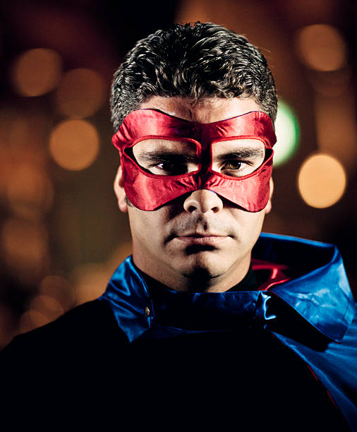 man with blue cape and red mask posing like a superhero, using LED lights.