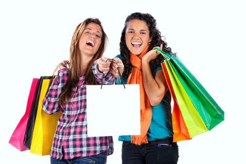 Two happy cute young women with shopping bags on white background