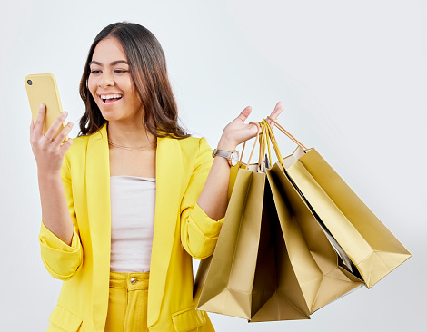 Fashion, phone or happy woman on social media with shopping bags for a sale, offer or discount code. Online, mobile app or excited girl customer with gift or present on promotion on white background