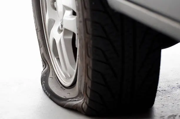 Photo of A flat tire is the focus isolated on white