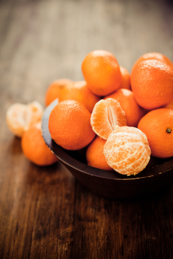 Citrus fruit: Clementines in a rustic wooden bowl.