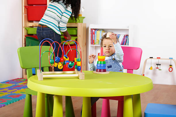 istock Toddler Playing With Multi-coloured Rings While Carer Tidies 154918282