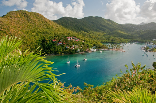 Caribbean beach with palms, turquoise water and boats on the shore with Gros Piton mountain in the background, Sugar beach, Saint  Lucia