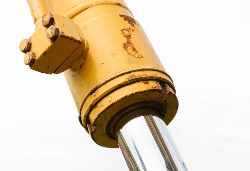 Detail of a heavy duty piston on an excavator. White cloud background.