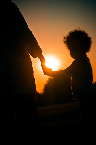 Royalty Free stock photo of 3 years old  little girl with her grandmother facing the sunset, shot to create silhouette. Addition of warm effect in post processing and vignette effect.