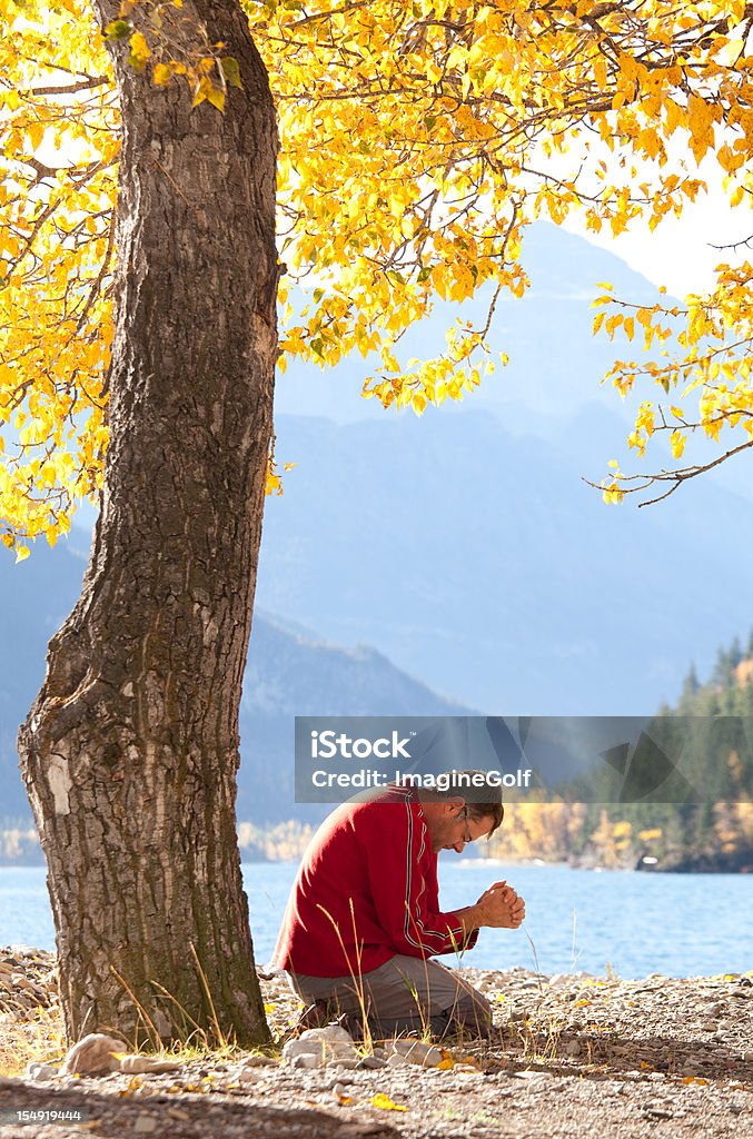 Caucasico uomo di pregare di fianco a un bellissimo lago di montagna - Foto stock royalty-free di Divinità