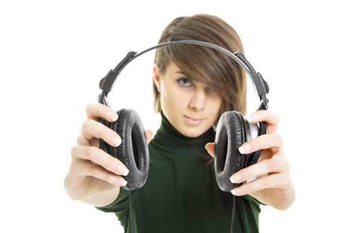 Young woman holding headphones.Focus on headphones.Isolated on white background.