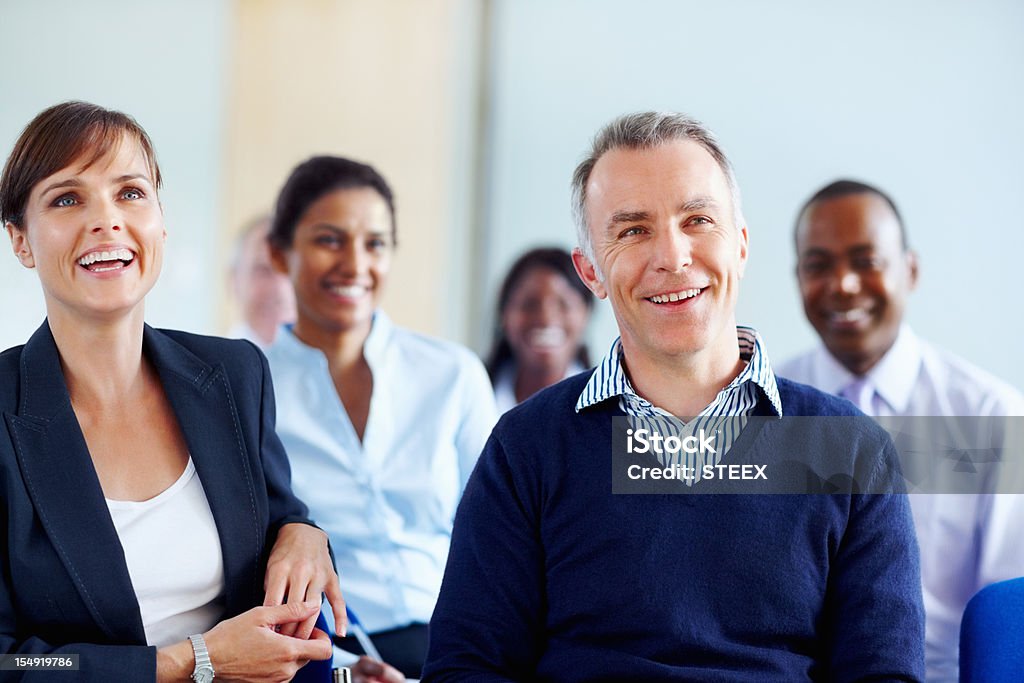 Executives smiling while listening presentation Group of executives listening to presentation 40-49 Years Stock Photo