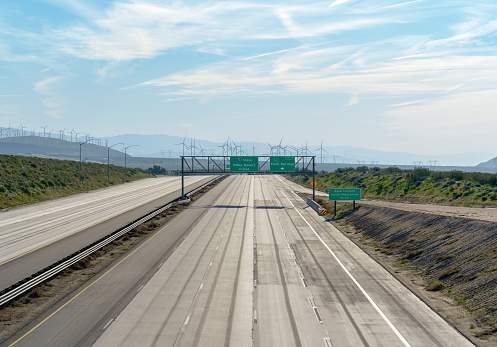 East on Interstate 10 in California near Palm Springs and Indio California. No cars on the freeway and windmills in the background.