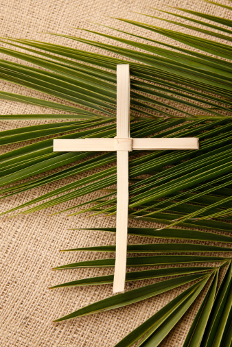 A palm cross on a burlap background.