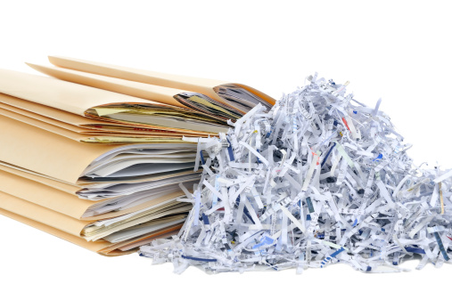 A stack of company documents next to recycled papers
