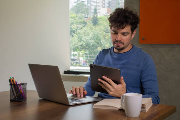 istock A focused young Latin man is working using a digital tablet at a casual workspace office. 1549211870