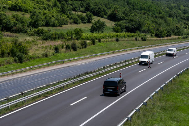 istock Two white Minivans and one black Minivan are moving slowly on the freeway in the opposite direction due to roadworks. 1549227032