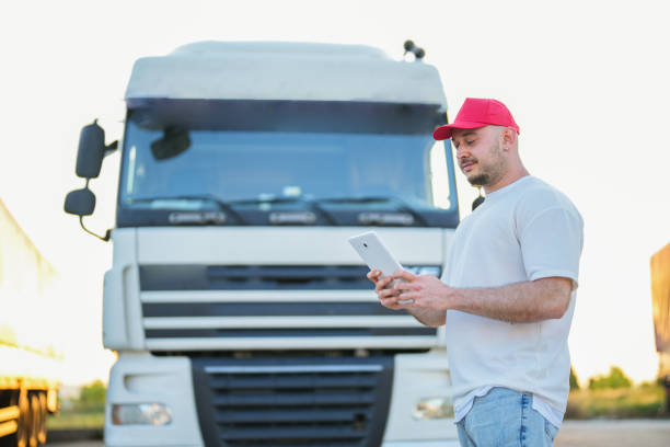 homem olhando para seu tablet na frente do caminhão branco - semi truck driver pride white - fotografias e filmes do acervo