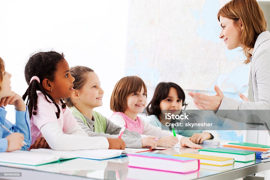 Insegnante che spiega ai bambini sono l'attività in Aula. - Foto stock royalty-free di Adulto