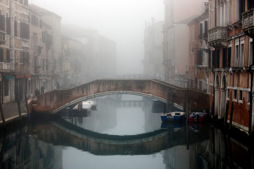 Gondolas in Venice at sunrise in morning fog. Veneto, Italy.