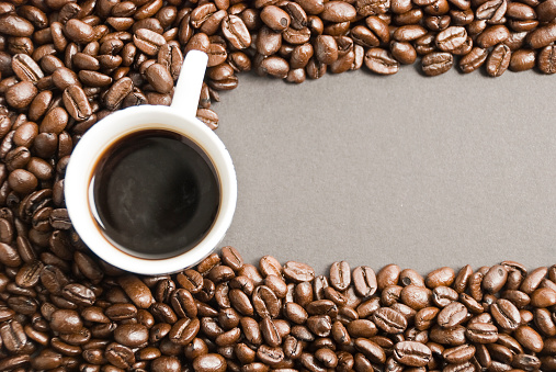 Cup of coffee with coffee beans on paper background. Top view photo