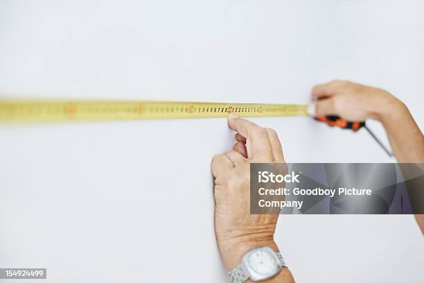 Handyman Using A Measuring Tape To Measure The Wall Stock Photo - Download Image Now