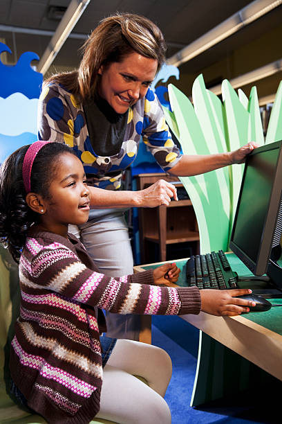 istock Teacher helping African American girl use computer 154925148