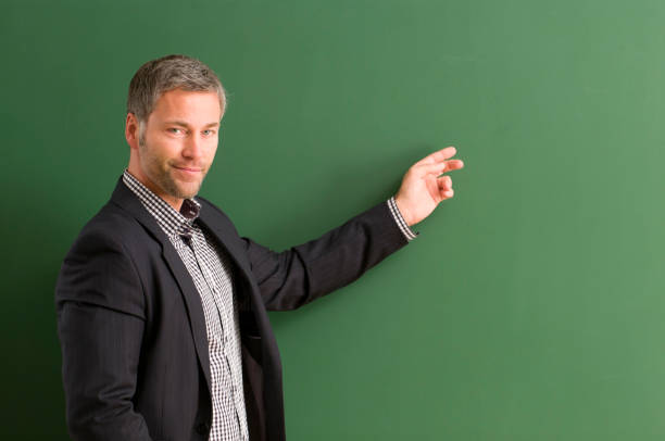 istock smiling teacher directing at blackboard 154925636