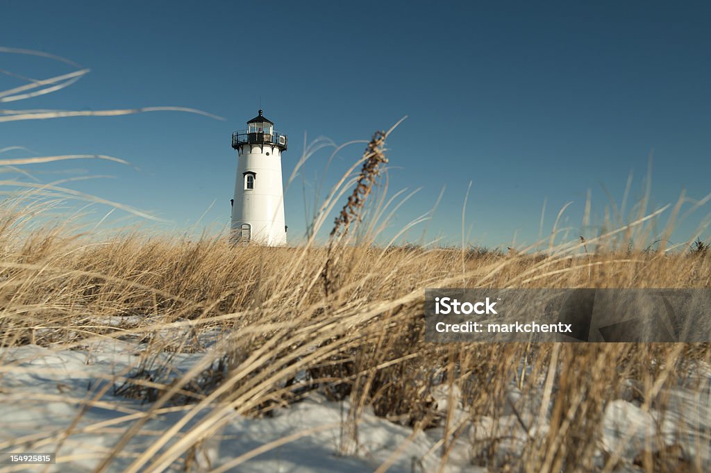 Ground level view of a lighthouse in Edgartown Cape Cod LIghthouse with dried grass and snow in the foreground Martha's Vineyard Stock Photo