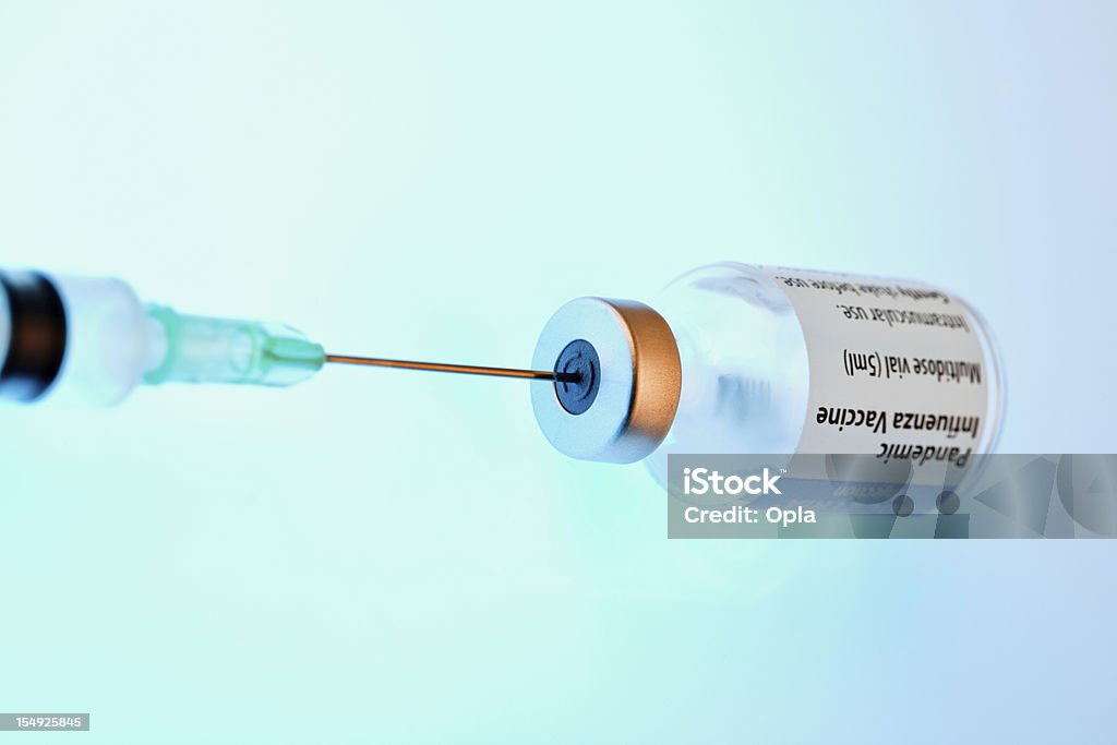Bottle of vaccine with syringe Bottle of vaccine with syringe in blue light Vaccination Stock Photo