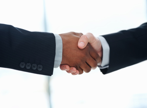 Two businessmen shaking hands after making deal in office