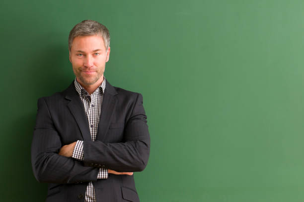 istock smiling teacher with arms crossed at blackboard 154925967