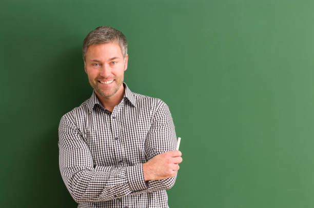 istock smiling teacher with arms crossed at blackboard 154925986