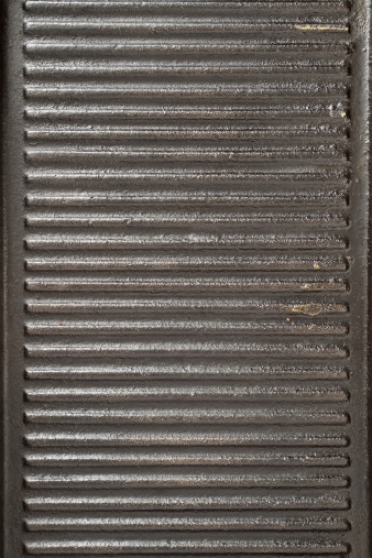 Top view of iron grill used to cook beef. It shows some dirt due to its use