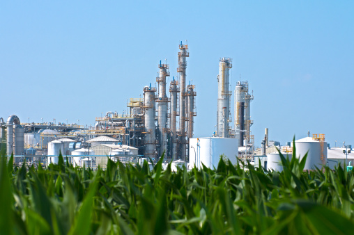 A sprawling industrial ethanol plant transforming corn as seen in the foreground into biofuel.