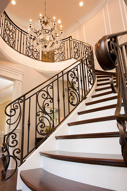 Interior view of a rustic wooden staircase with wrought iron railing, white plaster walls and natural light, showcasing eco-style architecture and handcrafted details.