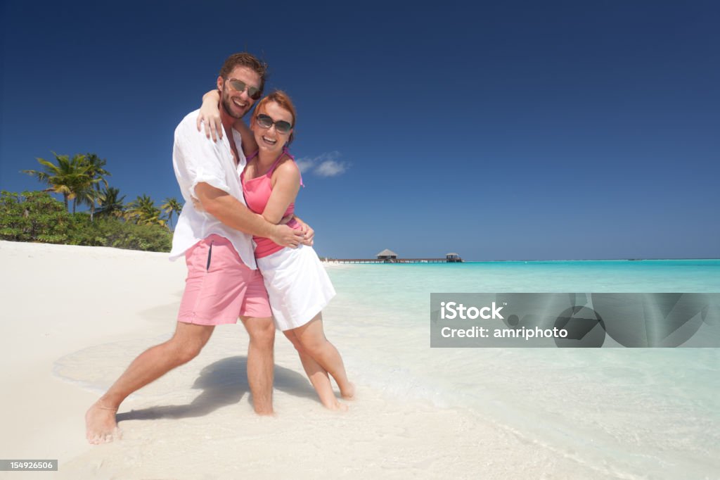 Sorridente giovane Coppia sulla spiaggia di sabbia - Foto stock royalty-free di Acqua