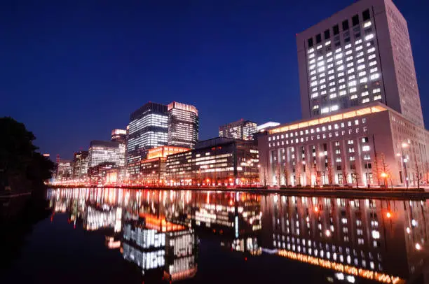 Wide angle shot of the Marunouchi (Hibiya) - Tokyo's prestigious financial and commercial center with the Imperial Gardens on the left at night.