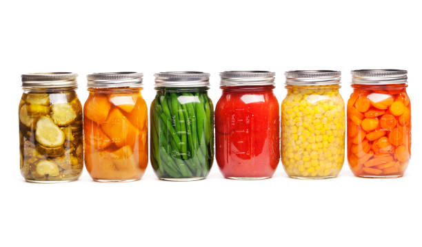 Canning Food Jars of Canned Vegetables Preserved in Glass Storage Row of canning jars featuring six different canned vegetables and fruits lined up and preserved in glass storage. The food varieties that are sauced, pickled, or sliced include carrots, green beans, tomatoes, corn, dill pickles, and sweet potatoes. Horizontal straight-on view, cut out and isolated on a white background. green bean vegetable bean green stock pictures, royalty-free photos & images