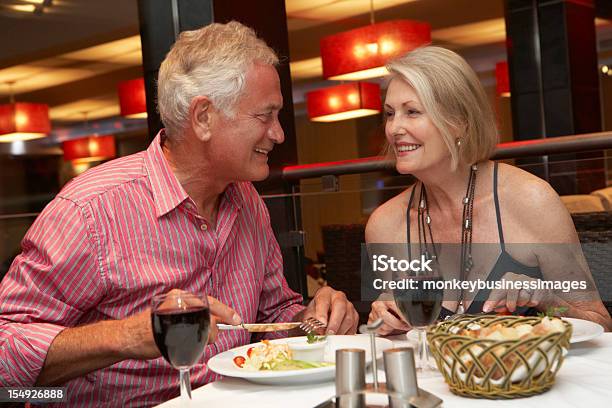 Senior Par Disfrutar De Comida En El Restaurante Foto de stock y más banco de imágenes de Sentarse a comer - Sentarse a comer, Pareja mayor, Parejas