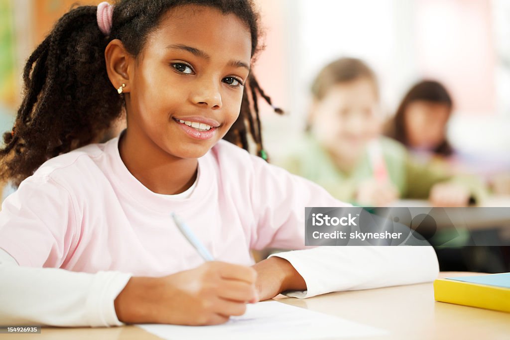 Girl is writing in her notebook at the classroom  African Ethnicity Stock Photo