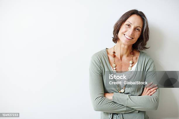 Elegant Middle Aged Woman With Her Arms Crossed Against White Stock Photo - Download Image Now