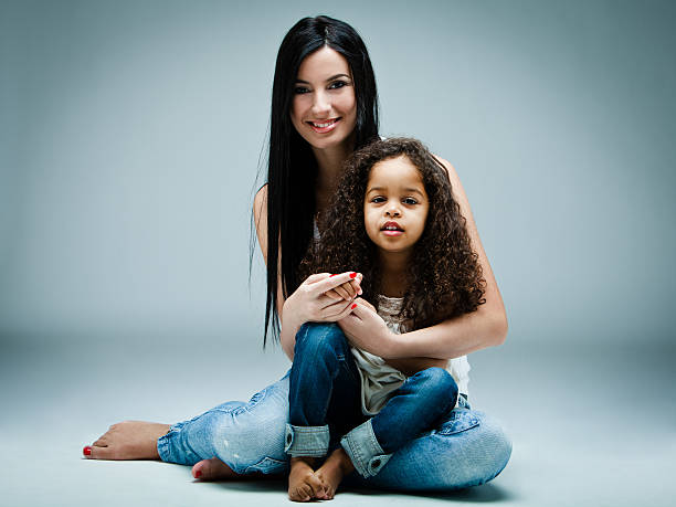 full length view of happy african american mother and daughter hugging and smiling at camera isolated on white