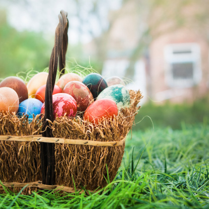 A basket of decorated Easter eggs sitting in the grass outside.