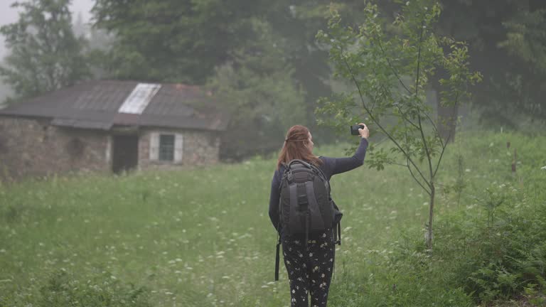 Beautiful female tourist taking selfie at camping area in nature.