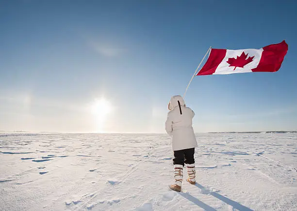 At -40C, a woman waves the Canadian flag while watching a rare display in the sky known as "Sundogs".  The bright center is the actual sun with the mirror images of it reflected in suspended ice crystals in the atmosphere.   This was taken on Great Slave Lake near Yellowknife in Canada's Arctic.