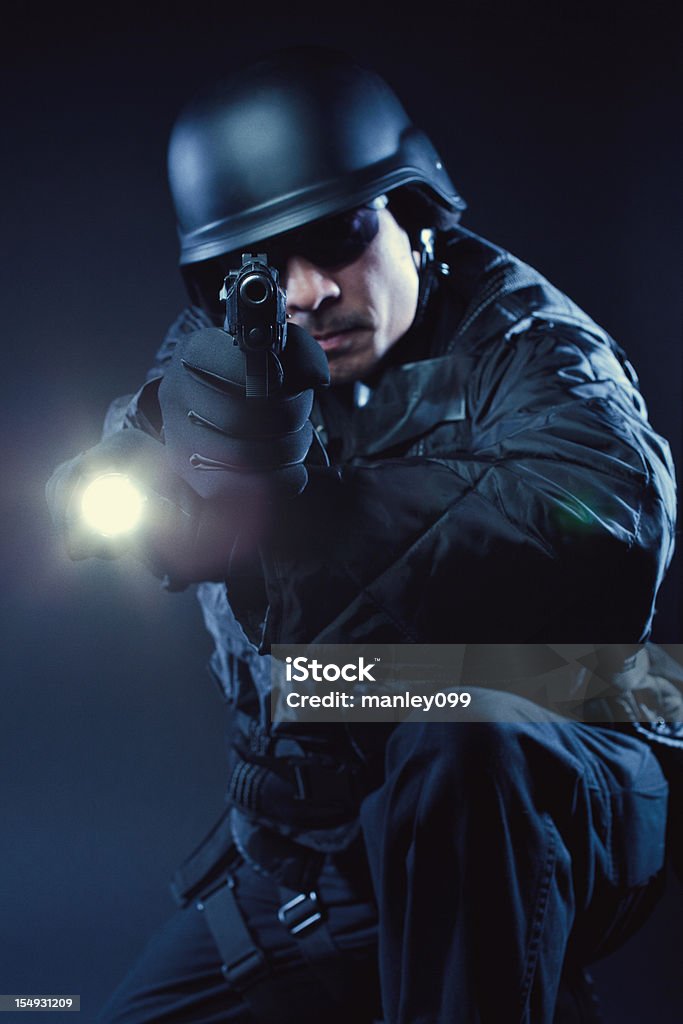Swat member kneeling with gun and flashlight  Adult Stock Photo
