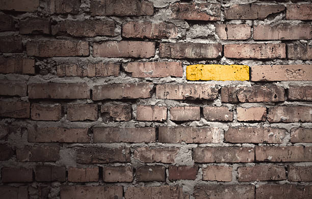 Brown brick wall with one gold brick stock photo